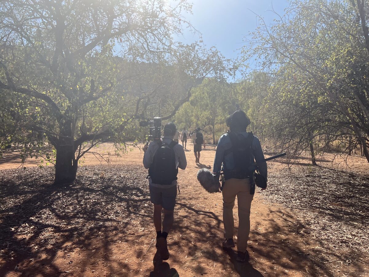 Film crew with camera and sound gear walking into a remote location shoot